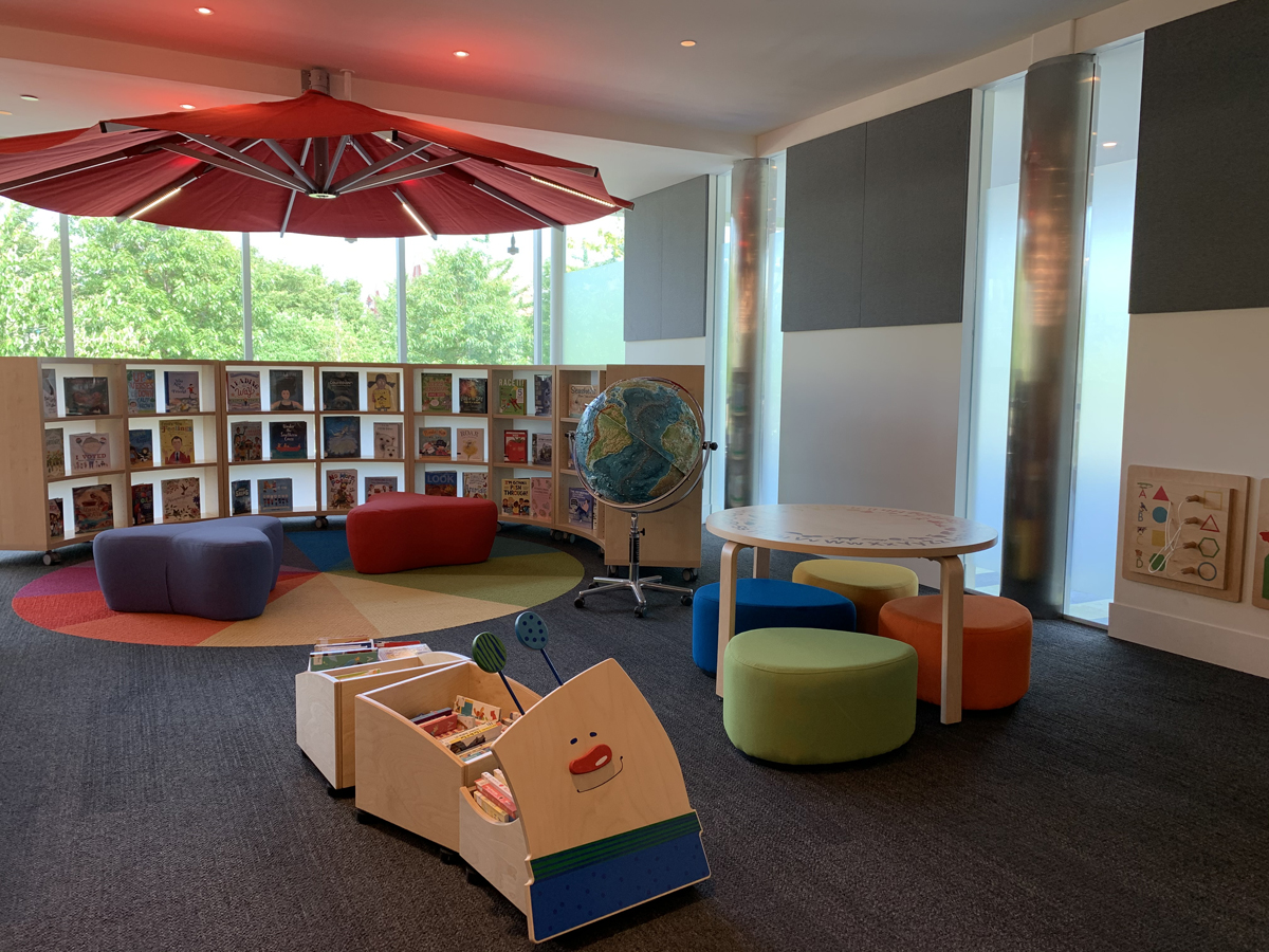 The new play area includes a spot for an activity table, Lego & train table, wooden interactive display walls, board book storage, a puppet theatre, and more.