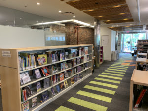 Shelving for new books is located next to the reference desk along the piano-key walkway.