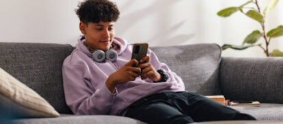 Young man sitting on a couch looking at their phone
