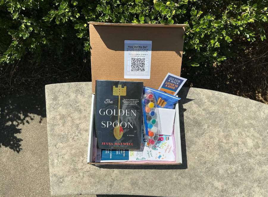 Opened book box with book, paints, snacks, and a bookmark