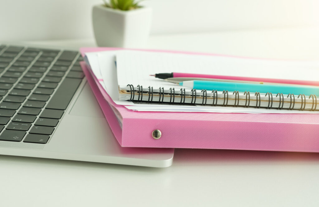Colorful folders of data report documents stack on manager table with blurred office equipment background.