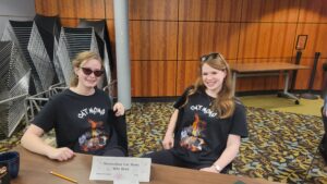two young women in cat shirts seated at table